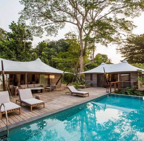 Pool with three loungers and in the background the three bedroom villa at Sundy Praia