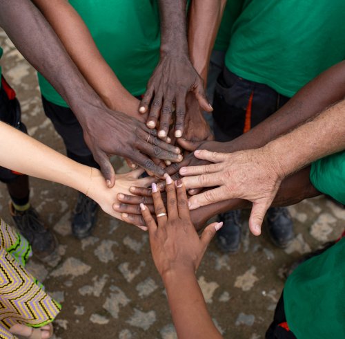 Circle of hands with different skin tones touching in the centre on Príncipe Island.