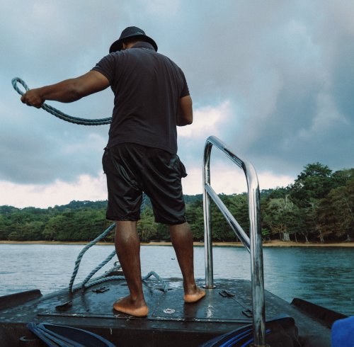 Man on a boat pulling up its anchor on Príncipe Island
