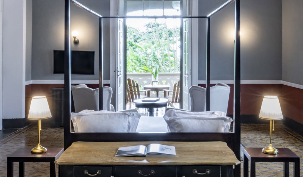 Spacious suite at Eclipse House in Roça Sundy with a four-poster bed, desk, and wooden ceiling