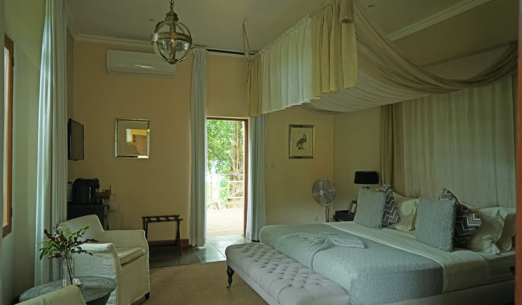 Spacious suite at Belo Monte with canopy bed, seating area and doors opening to a terrace among the trees.